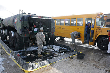 SPC Robert Sloppy dispenses fuel to a school bus while SPC Lauren Fratelli mans the pump valves. The two specialists, members of Delawares Aviation community, volunteered to deploy with the Delaware National Guard's 1049th as refueling specialists.