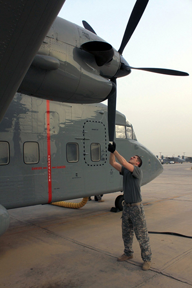 Sgt. Clint Walker, flight engineer with A Company, 641st Aviation Regiment, rotates the propeller of a C-23 Sherpa and checks it for damage and problems as part of his preflight checks and inspections.