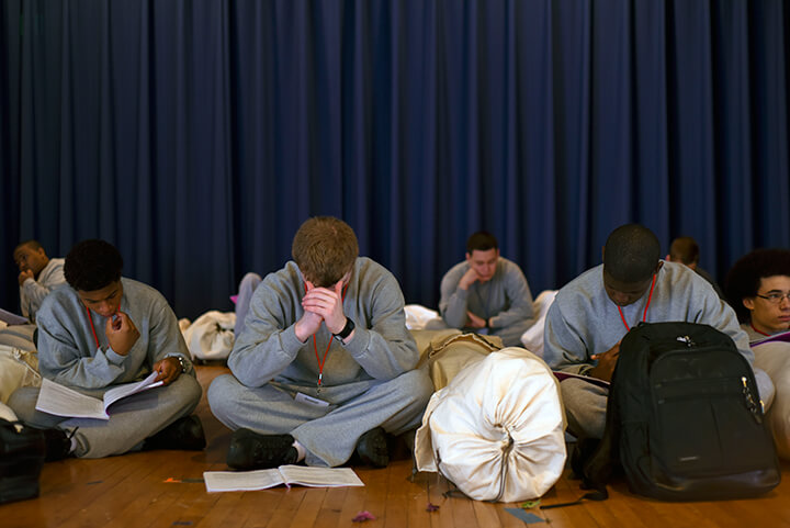 Candidates at the academy wait in a holding area with heads buried in their student handbooks.