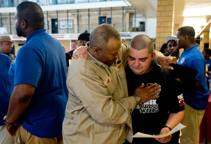 High school diploma in hand, Christopher Ramirez, right, is all emotions as Cpl. Kurt Jones, an academy cadre member, congratulates and praises him on his accomplishments. Ramirez was among the roughly 40 percent of his class to earn their diploma through the academy. Those cadets who did not earn their diploma during the residence phase will have the opportunity to retake the GED exam and earn their diplomas at a later date.