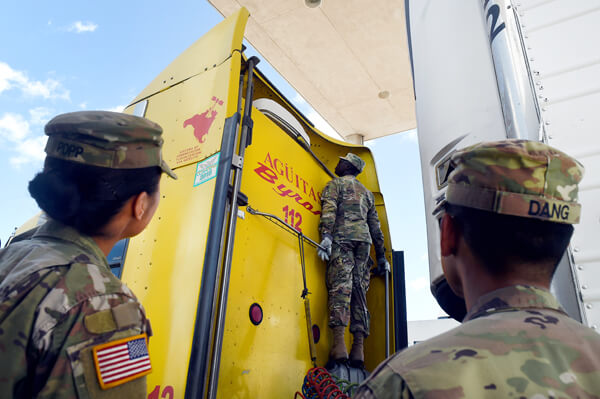 Checking certain areas may mean stretching to the fullest height possible as Aduhene, center, inspects a semi-truck while Popp, left, and Army Cpl. Paul Dang, a combat medic with C Company, 536th BSB, look on from the ground at the Pharr port of entry.