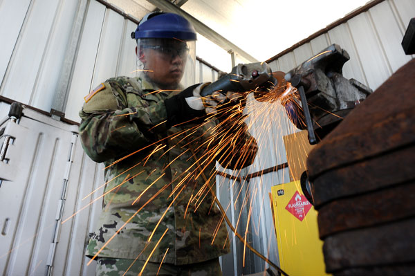 Army Pfc. Alex Vu, a combat engineer with Co. A, 172nd BEB, grinds a piece of metal while constructing a distress beacon at the McAllen, Texas, Border Patrol station.