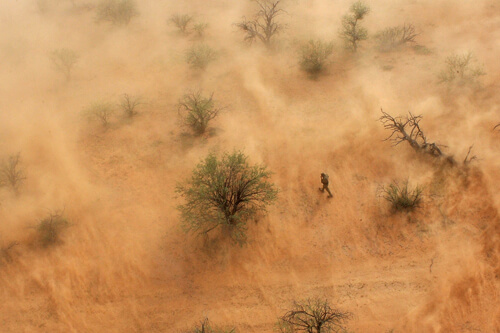 Kicked up by the rotor blades of the UH-60 hovering overhead, a whirlwind of dust swirls around an individual alleged to have crossed the border illegally. Part of a larger group, most were quickly detained by Border Patrol, though a few continued to push through the desert. Hovering above the individual, and moving with him, marked his location for agents on the ground.