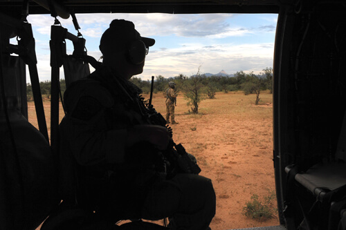 The helicopter rotor blades remain spinning as aircrew members and Border Patrol agents alike keep an eye out for a returning Border Patrol team after dropping them off to assist other agents in the field.