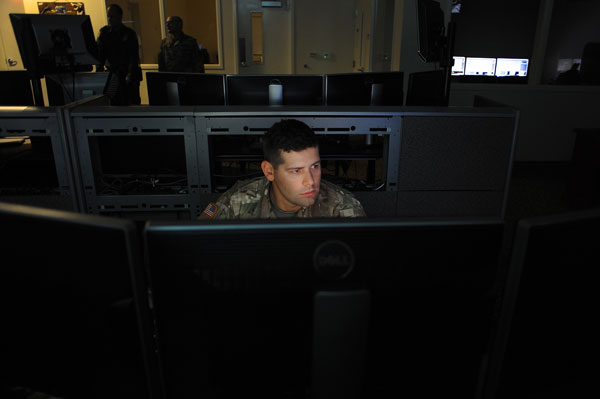 Lit by the radiant glow of computer monitors, Army Cpl. Scott Engels, a truck driver with the Arizona Army National Guard’s 222nd Transportation Company, keeps an eye on live feeds from surveillance cameras along the Arizona - Mexico border while working at the Border Patrol station in Nogales, Ariz. The cameras allow Engels, and others, to watch for illegal border crossings as well as cross-border drug smuggling and human trafficking.