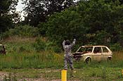 A 3rd Battalion, 142nd Aviation ground crew Soldier uses hand signals to the crew of the UH-60 Blackhawk air crew to complete the drop-off of the third abandoned vehicle during a GuardHELP community project in the Edgewood Oak Brush Plains Preserve near Ronkonkoma, Long Island.