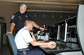 Air Guard Senior Master Sgt. Bret Patrick, detection systems specialist, speaks to a U.S. Customs and Border Protection agent while on duty at the Air and Marine Operations Center at March Air Reserve Base, Calif. Patrick monitors the radars that track aircraft flying into the United States, specifically watching out for potential drug smugglers. (National Guard Bureau photo by Air Guard Staff Sgt. Cheryl Hackley).