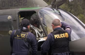  A Hawaii County police officer (left) and an agent of the Drug Enforcement Administration (right) confer with the pilot of a Hawaii Army National Guard OH-58 Kiowa before a joint marijuana-eradication mission on the Big Island of Hawaii. April 1, 2006 (by Steve Harding)