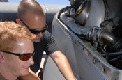 Staff Sgt. Ralph Beauvais and Staff Sgt. Joe Burriss, assigned to the 145th Airlift Wing of the North Carolina Air National Guard, take the engine cowling off engine number two in order to replace a fire loop on a C-130 Hercules before it flies out of McClellan Airfield, Sacramento on an airborne firefighting support mission July 4. The fire loop detects overheating and alerts crew members of possible issues in the C-130's engine.