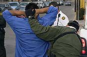 A Border Patrol agent apprehends a suspected illegal alien, who has just crossed the U.S. border with Mexico through a storm drain, in downtown Nogales, Ariz., on Jan. 17, 2007. National Guard Citizen-Soldiers and Airmen participating in Operation Jump Start monitor electronic surveillance equipment in remote control rooms and watch the border from observation posts, acting as the Border Patrol's eyes and ears. Since July 2006, information gathered by Guardmembers has helped the Border Patrol to apprehend more than 1,900 suspected illegal aliens or smugglers at the Nogales Station alone. Guardmembers do not come into direct contact with suspected aliens or smugglers. (U.S. Army photo by Sgt. Jim Greenhill)