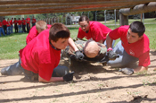 Kids attending the West Virginia National Guard's Youth Leaders Camp move a simulated litter patient through the demanding obstacle course at Camp Dawson. The annual week-long camp provides an opportunity for high-school aged kids to demonstrate leadership skills and develop self-confidence by completing a series of physical and mental challenges. (Photo courtesy of the West Virginia National Guard)