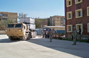 An armored tractor pulling a flatbed cargo trailer with 15 pallet boxes of donations is pulled into position in front of the orphanage. (Oliver)