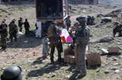 A French Soldier prepares a kite for an Afghan boy, while Sgt. Michael Mangulabnan of 3rd platoon, Company C 1st Battalion, 178th Infantry Regiment provides security and looks on during a humanitarian assistance drop on March 19. (Photo by 1st Lt. Lionel Gonzalez, Illinois National Guard)