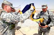 Army Col. Stephen Williams (left) commander of the 207th Infantry Brigade, Alaskan National Guard, and Command Sgt. Maj. Robert Averett (right) also with the ANG, unfurl their flag assuming command of the U.S. National Command Element in Southern Afghanistan here July 2, 2006. (Photo by Army Staff Sgt. Brian Raley)