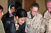 Master Sgt. Patricia Hughes (second from right), 177th Medical Squadron Public Health, 177th Fighter Wing, New Jersey Air National Guard; an Air Force doctor, an Army medic and two interpreters assess an Iraqi baby with an ear infection, mom is in the background. Hughes was assigned to the 447th Expeditionary Medical Squadron at Sather Air Base, Iraq.