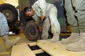 Spc. Geovany Soto, a light-wheeled vehicle mechanic with Headquarters and Headquarters Company, 130th Engineer Battalion, gets some help while opening a box containing a replacement Humvee radiator on Camp Liberty, Iraq, Wednesday, August 1, 2007. The 130th Eng. Bn. uses Humvees as well as other vehicle to clear routes of Improvied Explosive Devices in Iraq. (U.S. Army Photo by Sgt. S. Patrick McCollum) (Released)