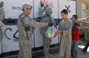 Specialist Gregory Dippel from Oswego hands a bag of personal hygiene items to on of the residents of the boys’ orphanage. (Ocque)