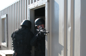  Members of the Regional Old Colony Special Operations Group provide rear security while other members of the group search and clear a building at the Maj. Jeffery R. Calero Military Operations in Urban Terrain training site on Camp Edwards, Mass., Jan. 29, 2009. The group is made up of law enforcement officers from eight agencies and serves high-risk warrants in 18 communities. The team has armed medics in case the need arises to stabilize an injured person before a scene can be declared safe for emergency medical technicians. (U.S. Army photo by Sgt. James C. Lally)