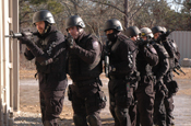 Members of the Old Colony Regional Special Operations Group prepare to search and clear a building at the Maj. Jeffery R. Calero Military Operations in Urban Terrain training site on Camp Edwards, Mass., Jan. 29, 2009. The OCRSOG used the MOUT training site to practice team movement techniques and room clearing procedures. The group is made up of law enforcement officers from eight agencies and serves high-risk warrants in 18 communities. (U.S. Army photo by Sgt. James C. Lally)