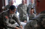 Indiana National Guard Soldiers with Task Force Cyclone, 38th Infantry Division, watch as Spc. Arianne Mora assembles an improved outer tactical vest after being issued equipment at Camp Atterbury Joint Maneuver Training Center, Ind., on July 15, 2009. (U.S. Army photo by Spc. William E. Henry, Indiana National Guard)