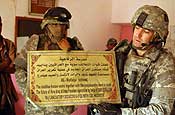 1st Lt. Michael G. Tarricone, a force protection officer for C-Troop, 5-117th Calvary, a New Jersey National Guard unit, holds up a sign donated by 13th Support Command (Expeditionary) during their first tour here at a school in Ajeelia, Iraq. (Photo by Spc. Alexandra Hemmerly-Brown, 210th Mobile Public Affairs Detachment)