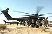 SOUTHWEST ASIA - Exiting Navy MH-53E 'Black Stallion' helicopters at an airport in Kuwait, California National Guard Soldiers from Company B, 2nd Battalion, 185th Armor Regiment carry their gear and an American flag. The Soldiers have spent the past 12 months in Iraq. (Photo by 40th Public Affairs Detachment)