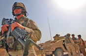 Tennessee National Guardsman Sgt. 1st Class Joel Gibbons, Cavalry Scout platoon Sgt., 1st Squadron, 278th Regimental Combat Team, Task Force Liberty, stands guard while an Iraqi child passes information of a weapons cache found near the Iranian border to the commander of the unit, Capt James Hite. Tons of ordinance were abandon after the war with Iran and has been a source of explosives for bomb making insurgents.