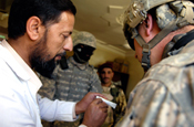 An Iraqi doctor talks with U.S. Army Spc. Ross Kellogg, a combat medic, with 3rd Platoon, Bravo Company, 1st Battalion 161st Infantry, 81st Brigade Combat Team (Heavy), Washington Army National Guard, during a medical supply drop at a clinic in the Abu Sayf District of Mosul, Iraq, June 1, 2009. (Photo by Senior Airman Kamaile O. Chan, Joint Combat Camera Center-Iraq)